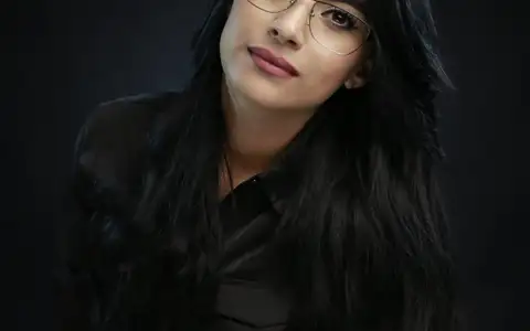 Portrait professionnel d'une femme à lunettes sur fond sombre