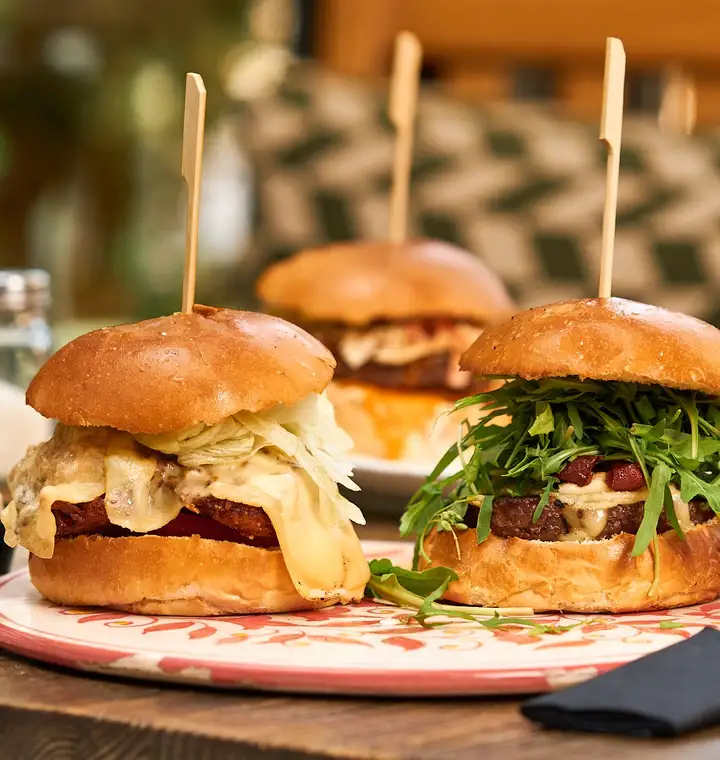 Burgers garnis de roquette et de chips servis sur une planche en bois en terrasse
