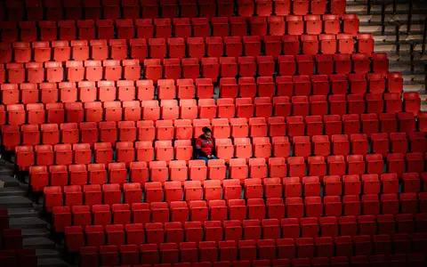 Supporter isolé dans les tribunes rouges d'un stade pendant la CAN 2025