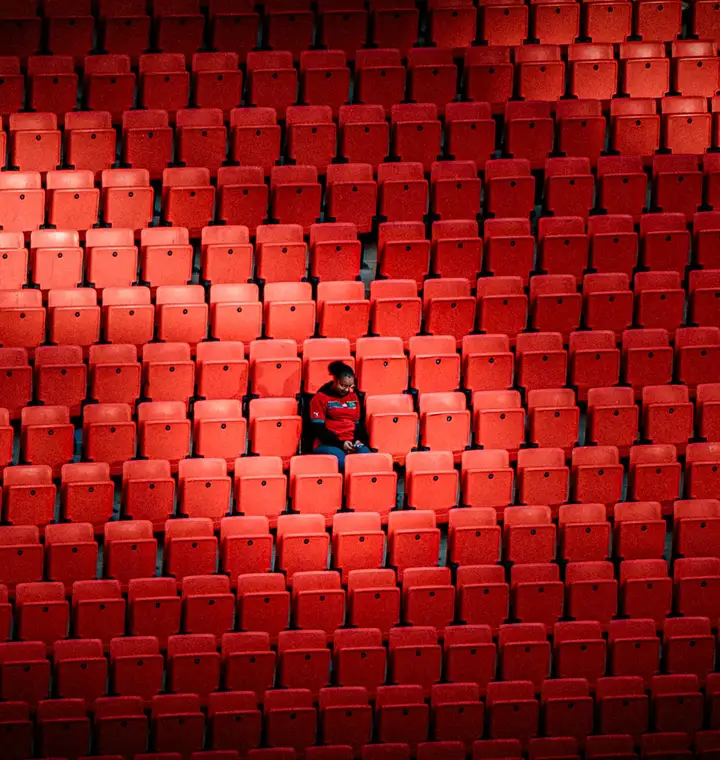 Supporter isolé dans les tribunes rouges d'un stade pendant la CAN 2025