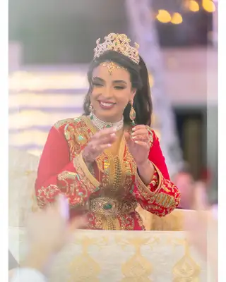 Mariée en caftan rouge et or applaudissant pendant la réception