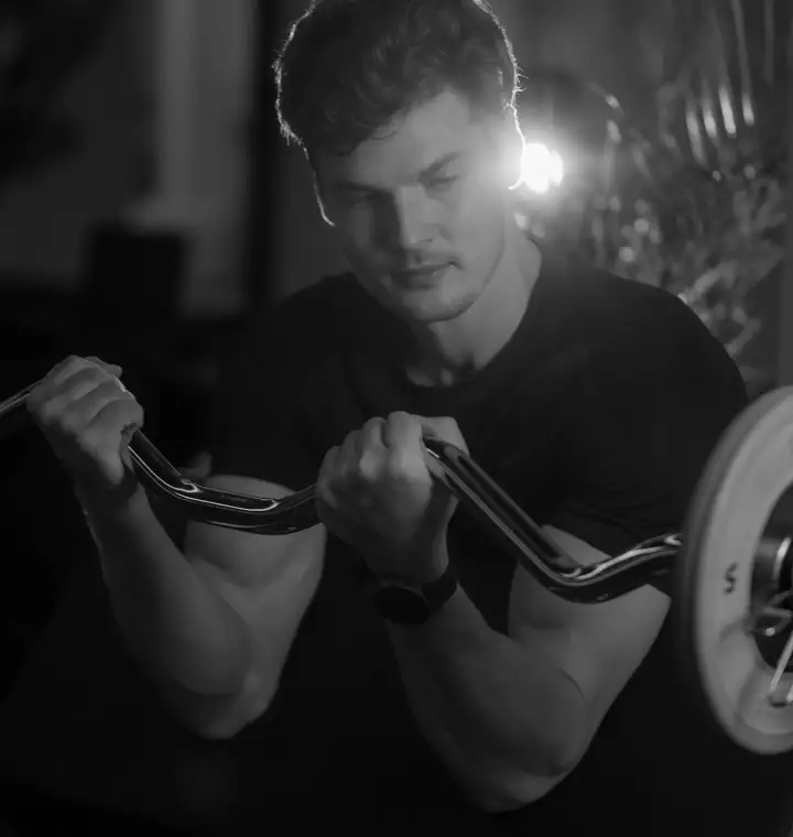 Athlète travaillant les biceps à la barre EZ en salle de sport, en noir et blanc