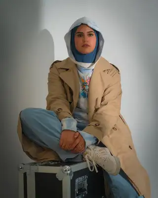 Modèle assise jambes croisées sur une flight case, fond blanc