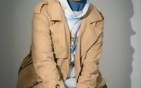 Portrait souriant en trench beige et foulard bleu sous éclairage studio