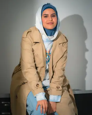 Portrait souriant en trench beige et foulard bleu sous éclairage studio