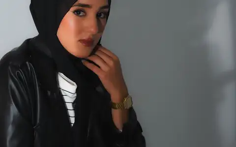 Modèle en veste en cuir noir, la main sous le menton