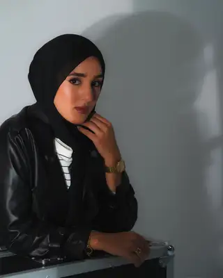 Modèle en veste en cuir noir, la main sous le menton