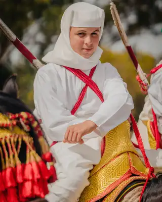 Jeune cavalier en tenue blanche et baudrier rouge, le fusil à l'épaule