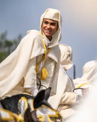 Cavalier souriant en tenue blanche traditionnelle sur son cheval lors d'un moussem